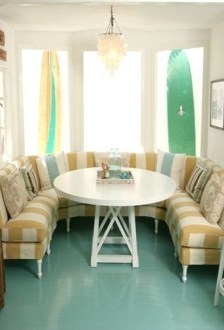 Breakfast nook with turquoise high gloss painted wood floor, two surfboards as decoration and yellow and white stripped banquette seating