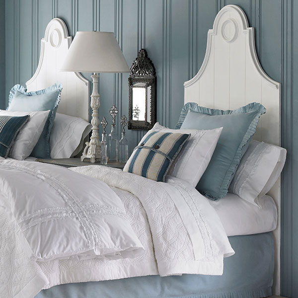 White French country headboards in a bedroom with blue wood paneling