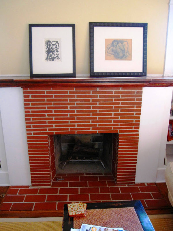 Exposed brick fireplace in a Venice Beach home with two sketches in dark frames on the mantel