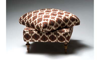 Ottoman with turned wood legs uphostered in brown, white and black ikat fabric from Madeline Weinrib