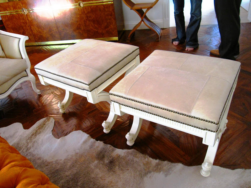 Two small stools with white legs and nail head trim in a living room in a Los Angeles home