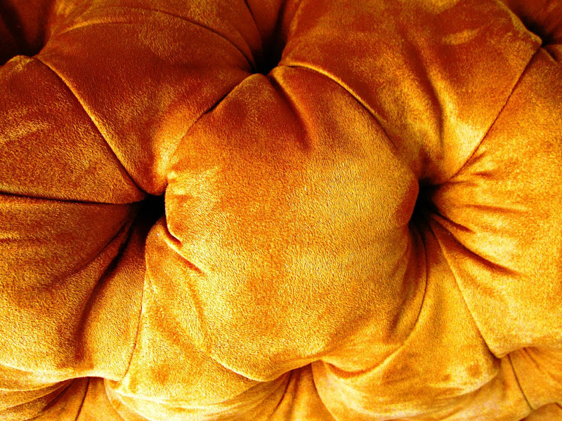 Close up of an orange suede tufted ottoman 
