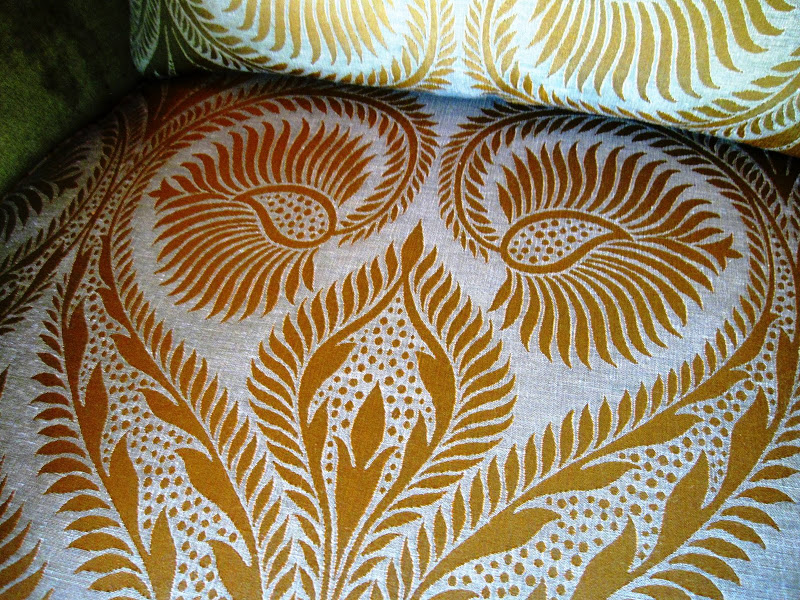 Close up of the a peacock paisley fabric on a velvet avocado green armchairs