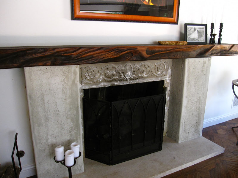 A stone fireplace with a wood beam mantel in a living room in a Los Angeles home