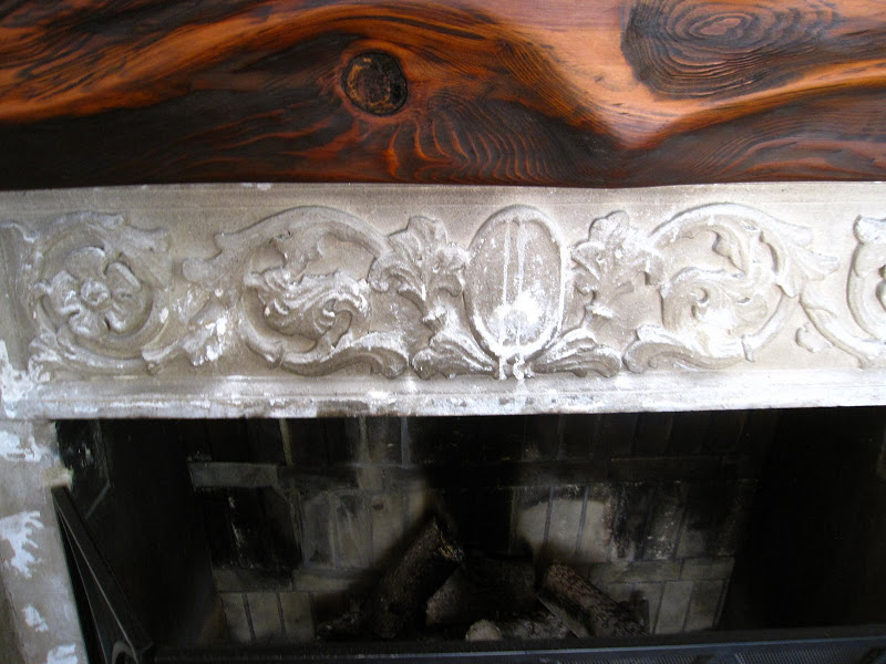 Close up of the rough carved designs on a stone fireplace with a wood beam mantel