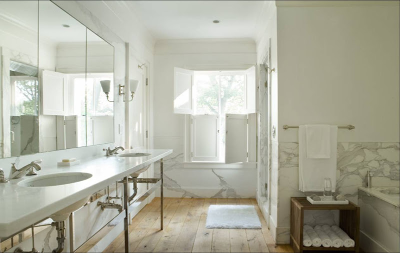 Spa like bathroom with white marble walls, unfinished wide plank wood floors and classic double sink