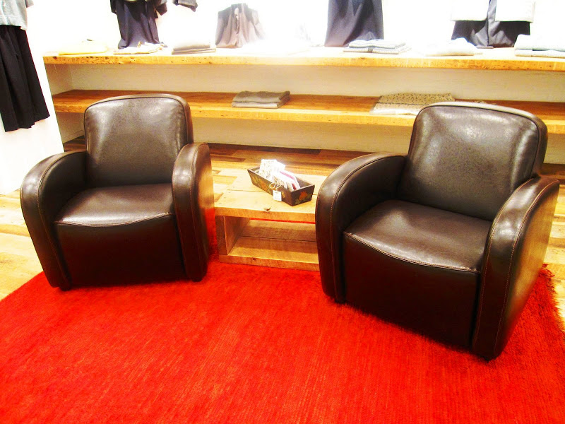 Two brown leather club chairs are set on a bright red rug in Neiman Marcus