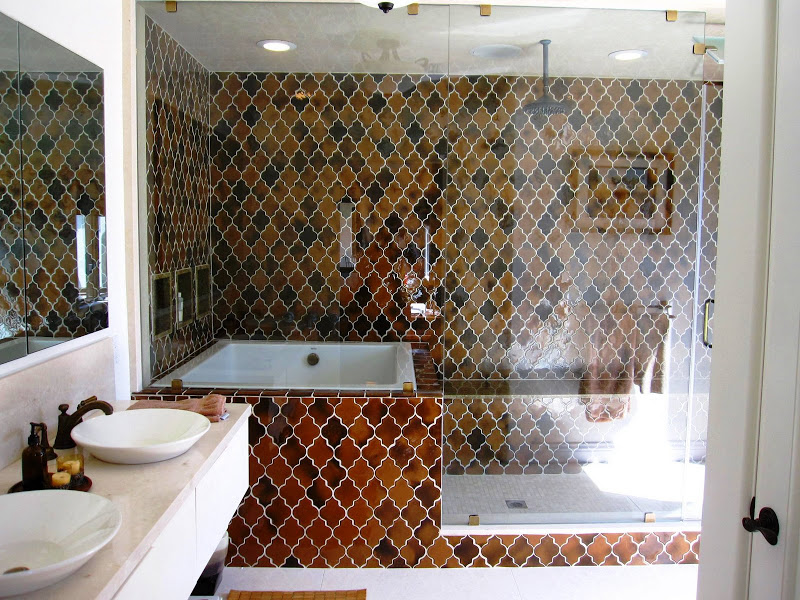 Bathroom in a Los Angeles home with a glass enclosed combination tub and shower with bronze glazed tiles