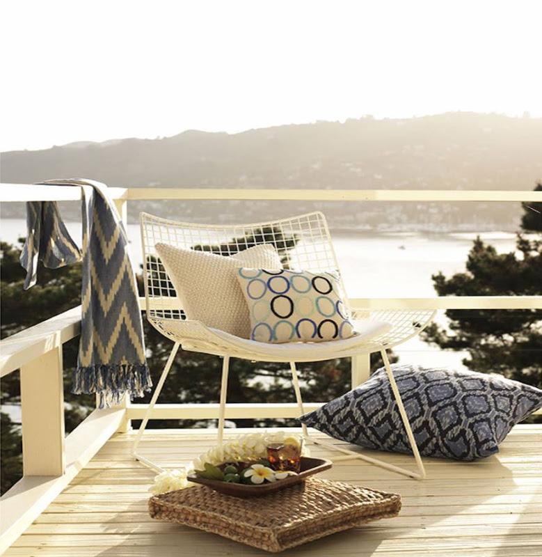 White wire outdoor chair sits on a deck overlooking the ocean by Sang An