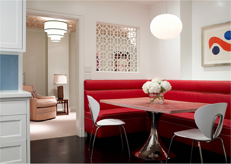 Breakfast nook with red leather corner banquette seating, a table with a chrome tulip inspired base with a square stone top and dark wood floor