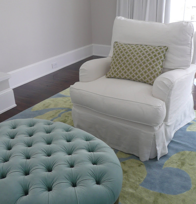 White armchair and a round tufted turquoise ottoman in a bedroom by Brooke Giannetti