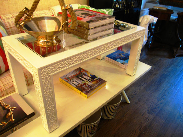 Rectangular white lacquer coffee table with glass top and carved fretwork detailing on the side and legs inside the Elizabeth Bauer store