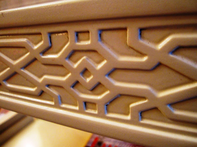 Close up of the carved geometric fretwork detailing on the side of a white lacquer coffee table inside the Elizabeth Bauer store
