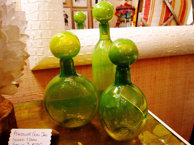 Three green hand blown glass bottles inside the Elizabeth Bauer store