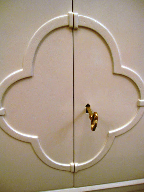 Quatrefoil design surrounding a brass key and lock on a white lacquer side table inside the Elizabeth Bauer store
