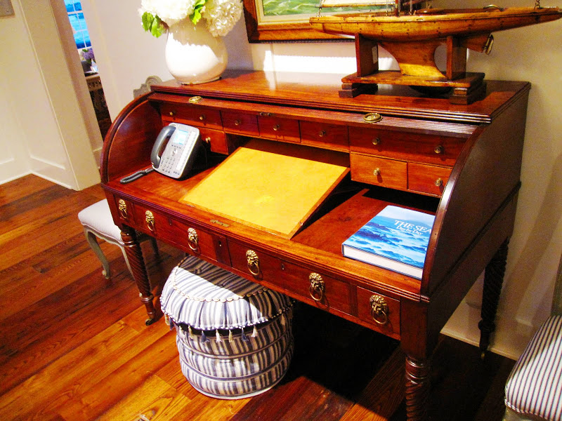 Antique roll top writing desk in the Great Harbor Yacht Club's formal living room with a striped ottoman with blue and white tassels