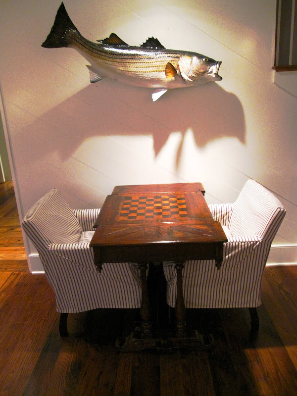 Fish wall hanging over a wood game table with two slip covered side chairs at the Great Harbor Yacht Club