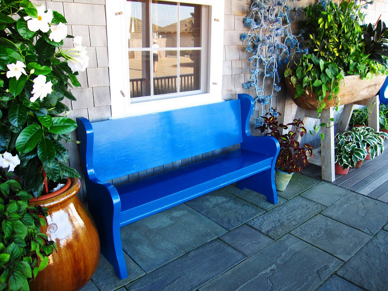 Glossy bright blue bench under a window on a beach front porch in Nantucket