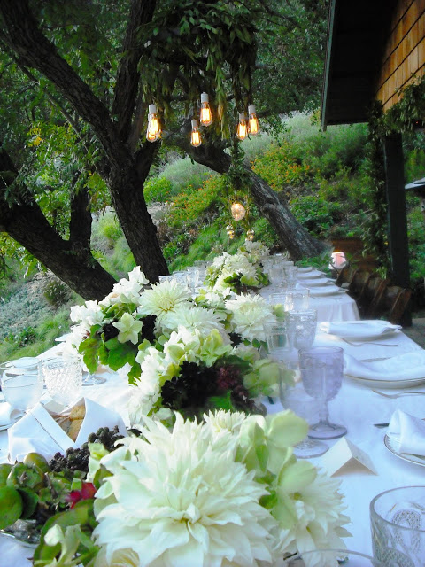 Elegant flower arrangement flows down the center of the two long tables at an outdoor wedding