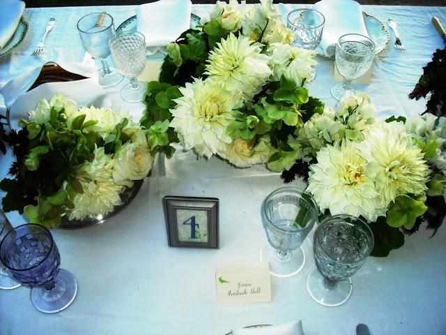 Outdoor wedding table setting with a mix of vintage plates, silverware and glasses