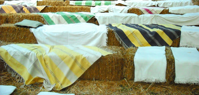 Seating at an outdoor wedding on a hillside made of bales of hay and colorful Mexican blankets