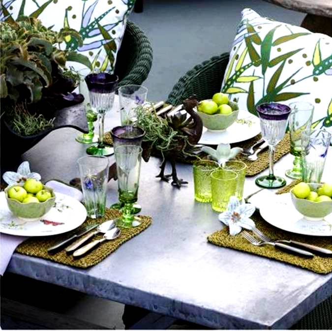 Elegant table setting with green glasses, purple rimmed wine and beer glasses, woven place mates and white plates and dinnerwear