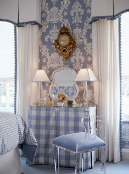 Blue bedroom by Kelley Proxmire with a vanity with a blue and white gingham skirt, blue and white damask wallpaper, vintage gold wall clock, white vintage mirror and a lucite chair