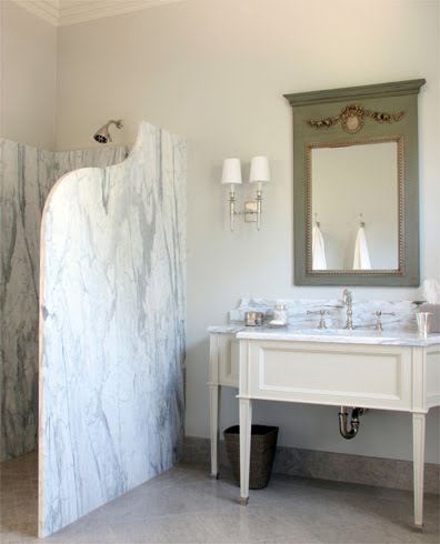 French bathroom with trumeau style mirror and a curved marble slab shower screen