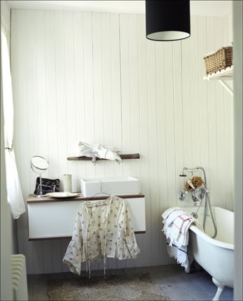Country bathroom with white beadboard walls, floating wall mounted vanity, white claw foot tub and a black pendant light