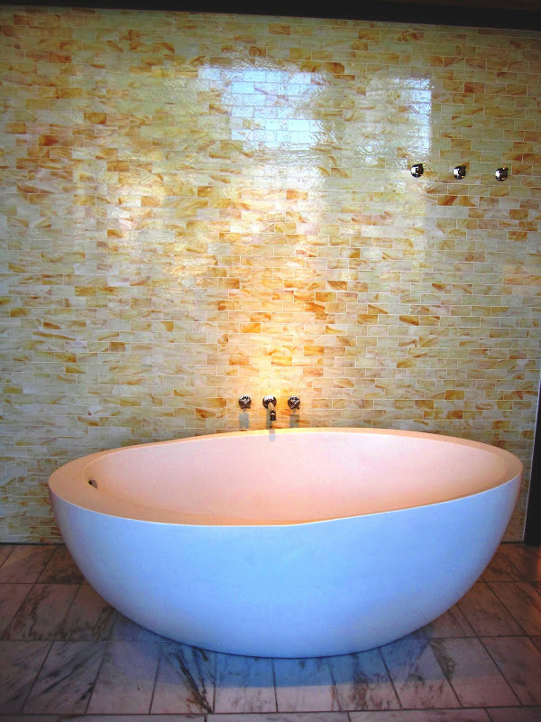 Bathroom with yellow marble mosaic subway tile wall, modern egg shaped freestanding tub and marble floor