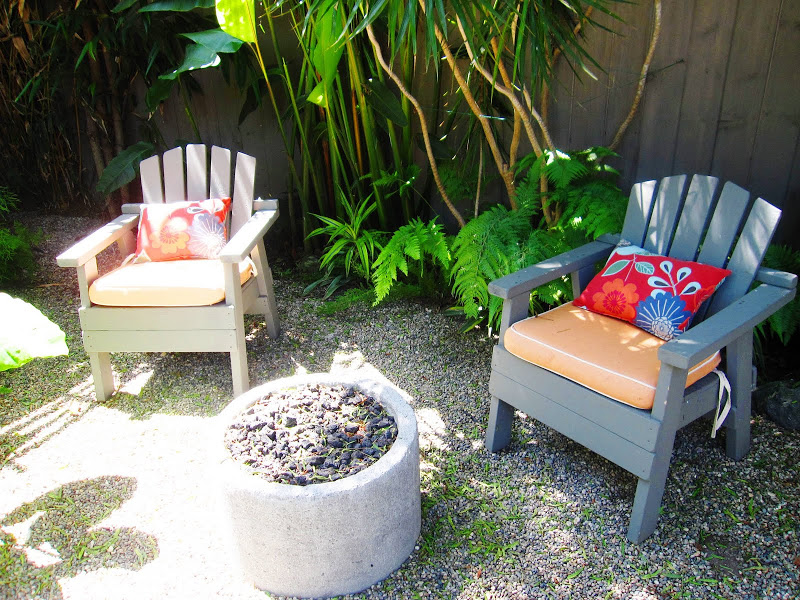 Outdoor chairs with bright accent pillows around a fire pit in a backyard in Venice Beach, CA