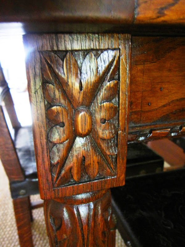 Close up of the carved details on an antique dark stained wood dining table