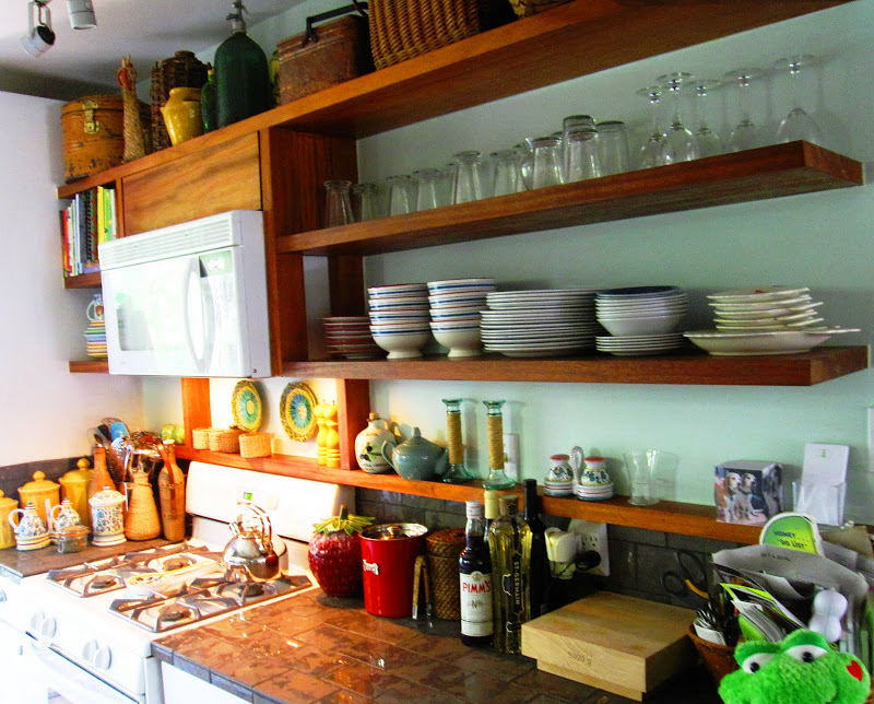 Gallery kitchen with open wood shelves holding antique finds and ceramic dishware