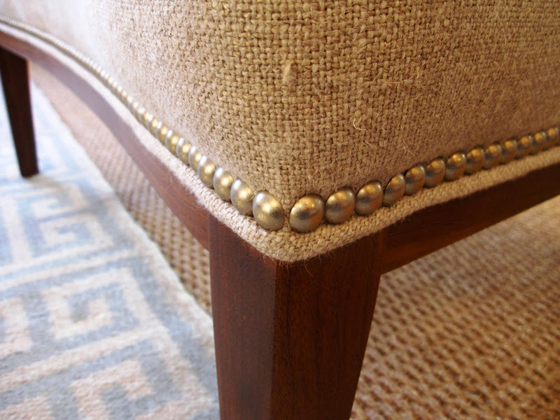Close up of the nail head trim on a n extra wide upholstered chair in the Jonathan Adler store 