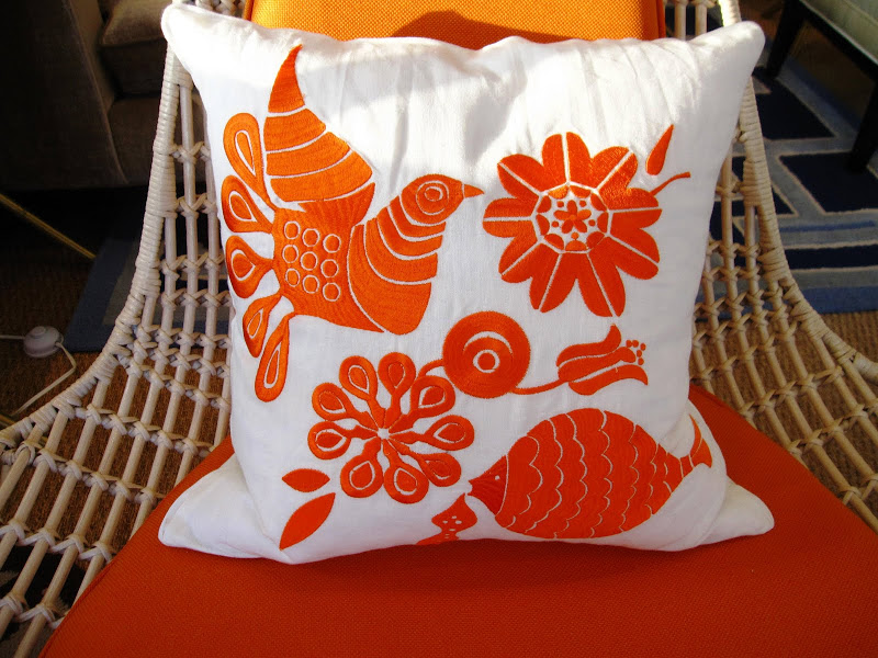 Orange and white embroidered pillow in the Jonathan Adler store