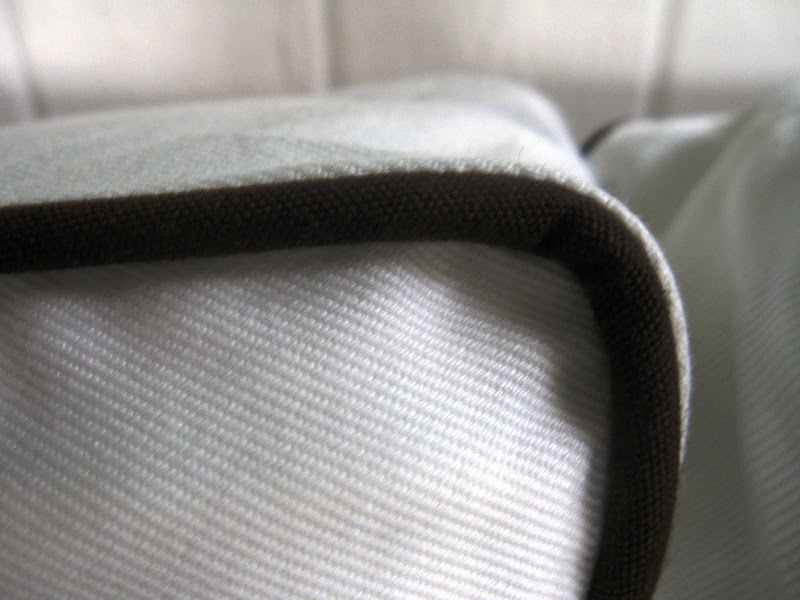 Close up of the chocolate brown piping on a white slipcovered armchair 