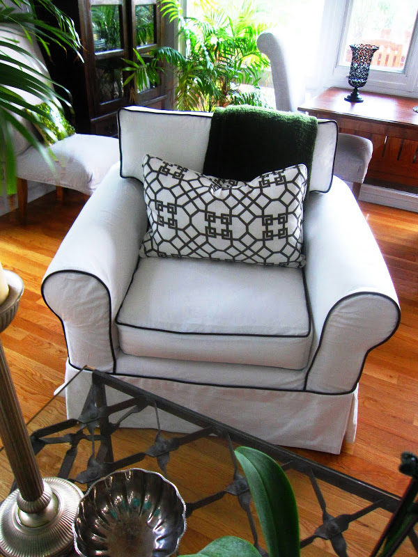 White slipcovered armchair with chocolate brown piping and a custom Windsor Smith pillow in a living room