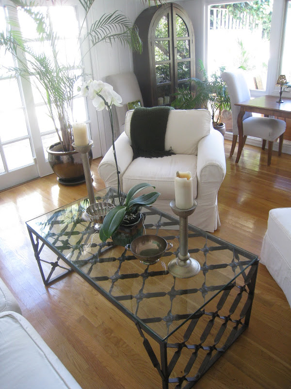 White cotton duck armchair in a living room with an iron coffee table with a glass top