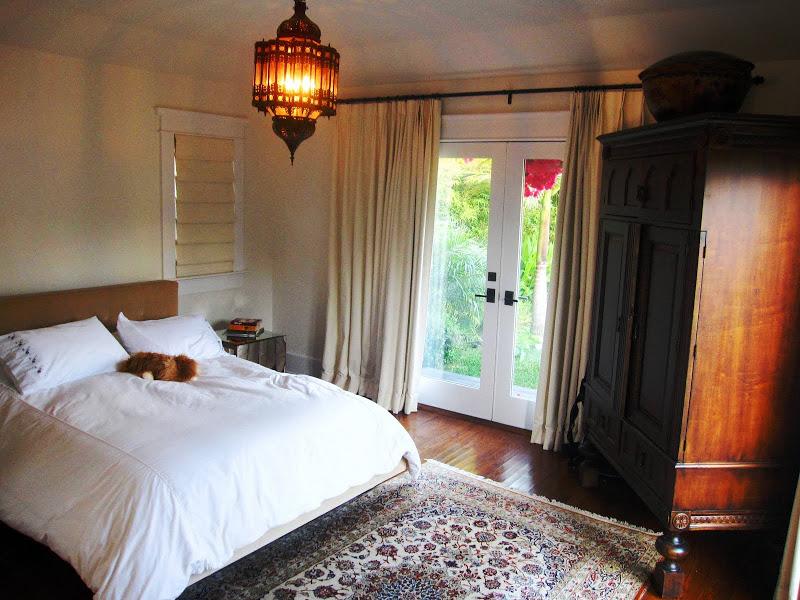 Bedroom in a beach house with a large Moroccan style metal lantern, wooden wardrobe and a Persian rug