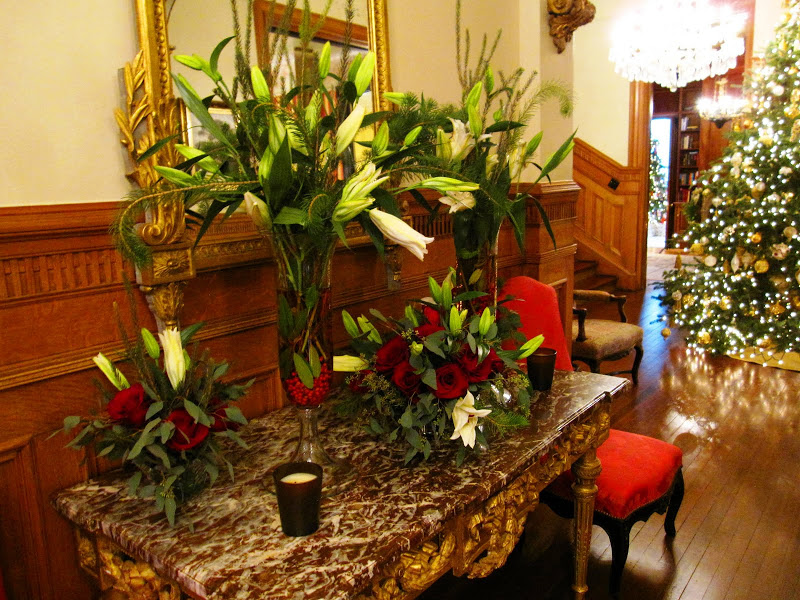Main entry hall in a historic New Orleans mansion with a flower arrangement of white star gazer lilies, pine tree branches, eucalyptus leaves, red berries and a touch of red food coloring