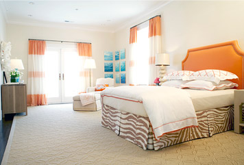 Bedroom by Massucco Warner Miller with an orange upholstered headboard, orange and cream striped curtains and a zebra print bedskirt