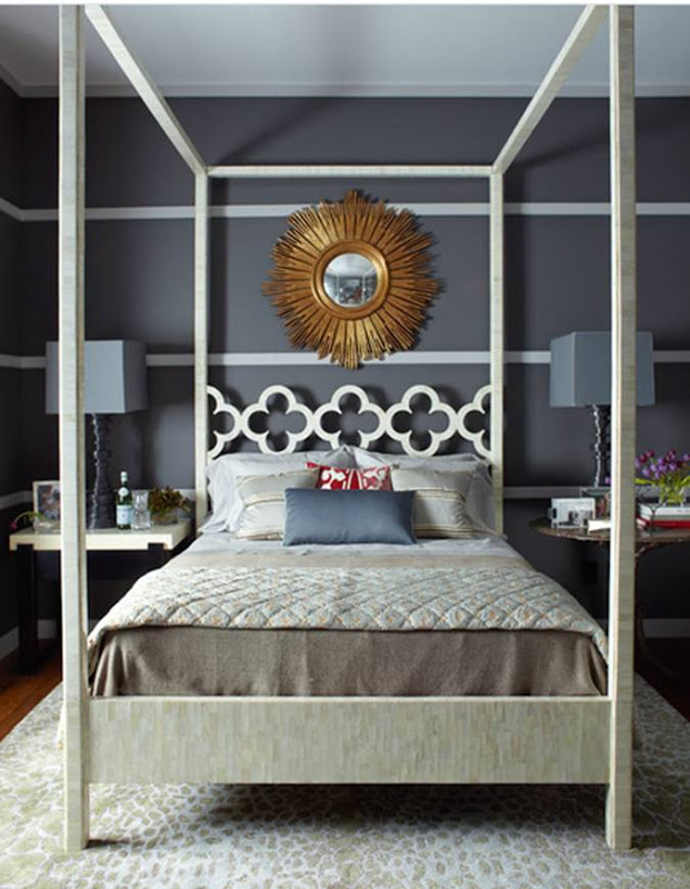 Bedroom with dark grey walls with white stripes, a white canopy bed, a sunburst mirror, mismatched nightstands and a white and tan rug