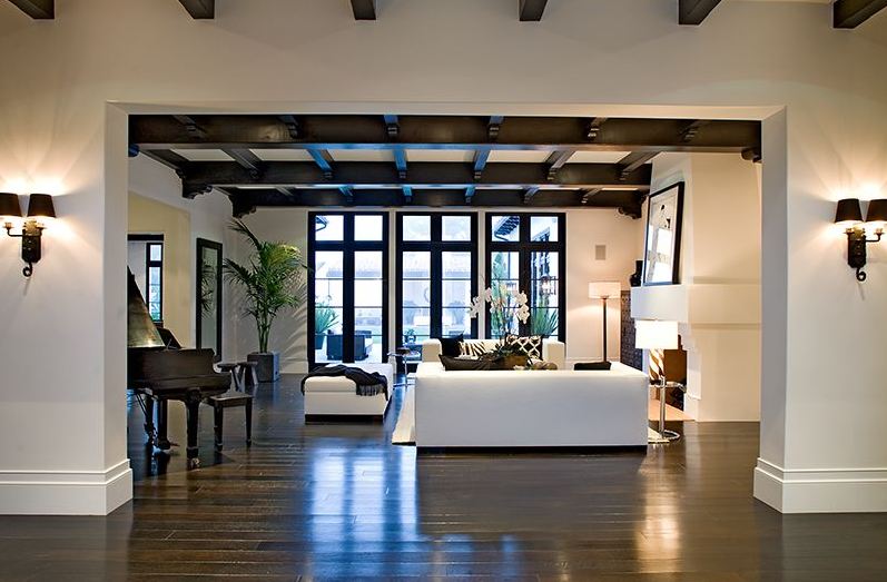Foyer in a Spanish revival home with painted black exposed beams and a view of the living room