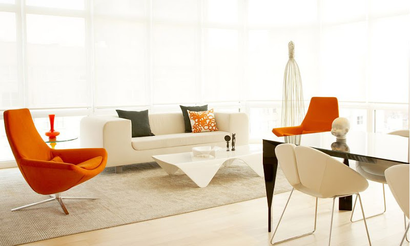 White living room with wrap around windows and modern orange chairs
