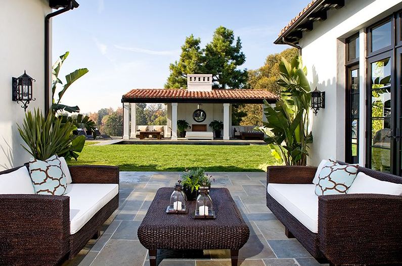 Outdoor seating area with wicker sofas with white cushions in a Spanish revival style home in Los Angeles