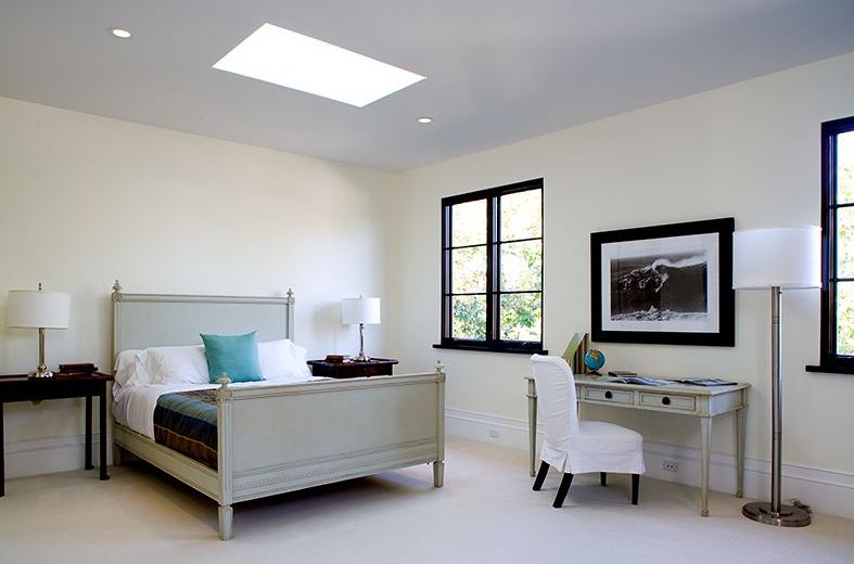 Bedroom in a Spanish Revival home with black paned windows, a skylights and matching grey bed frame and desk