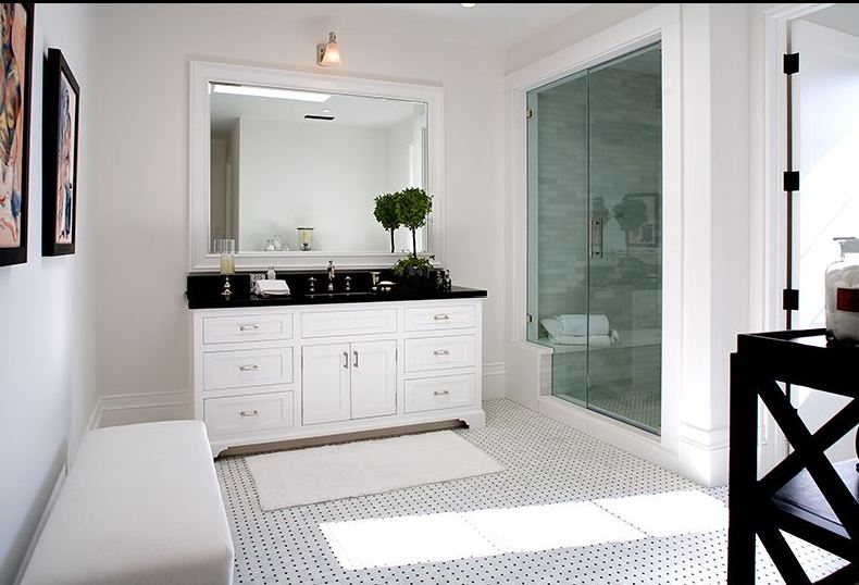 Black and white Master bathroom in a Spanish revival home with glass shower and a white bench