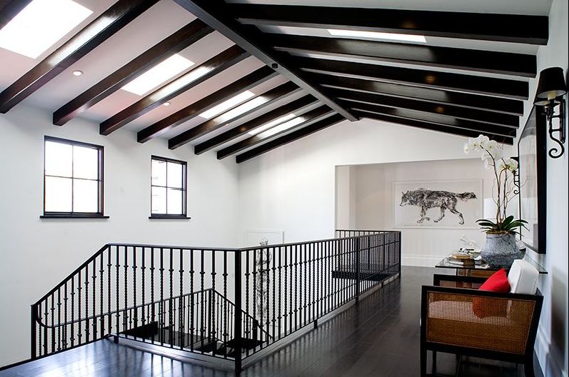 Second floor hallway in a Spanish Revival home with exposed painted black beams