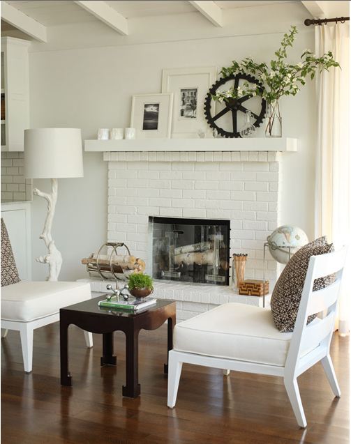 White painted brick fireplace flanked by two white lounge chairs in a living room