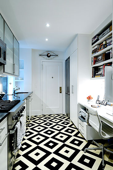 Kitchen with diamond patterned black and white tile floor, white cabinets and a built in desk